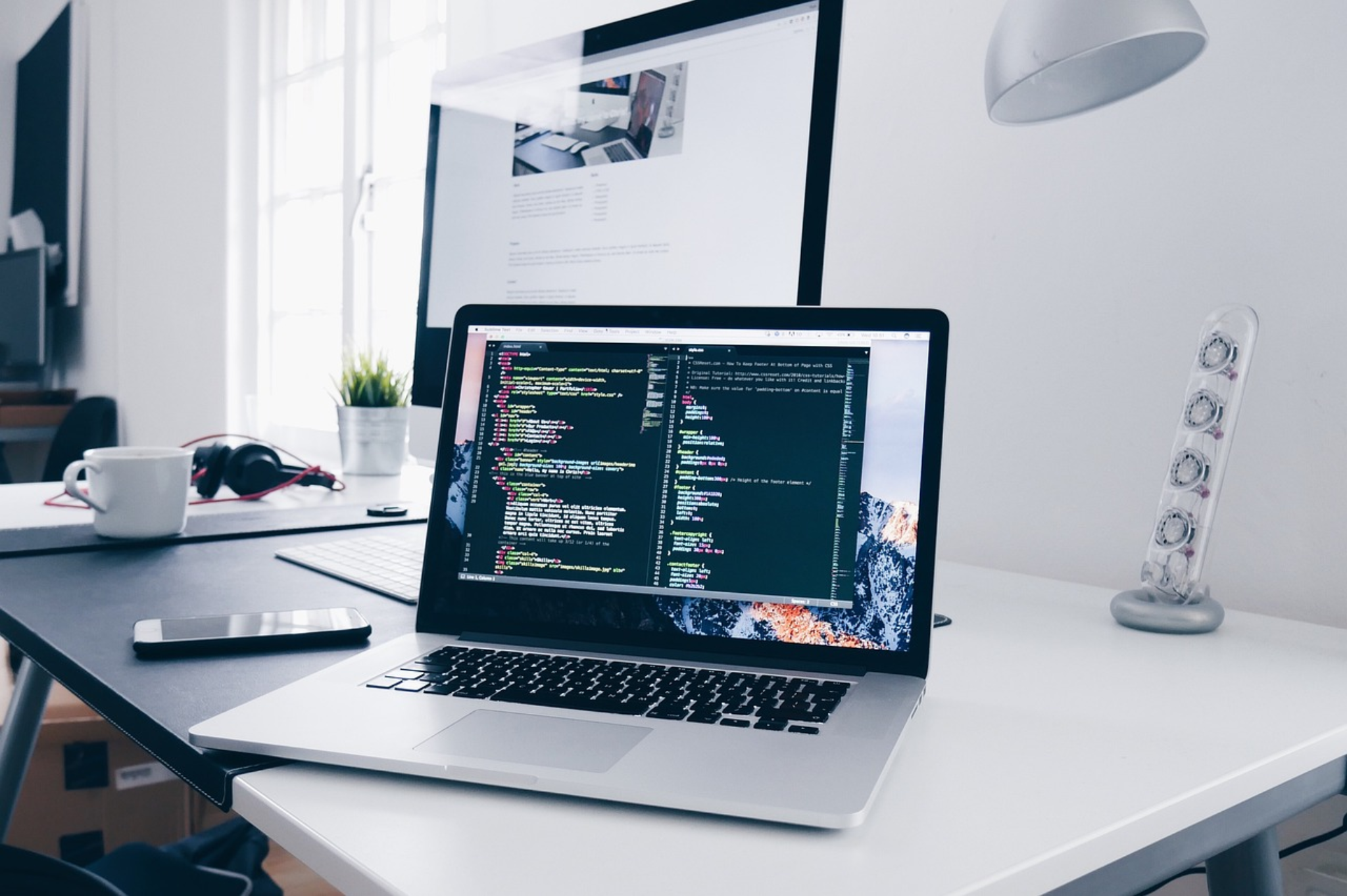 Developer workspace with laptop, code and monitor